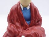 a figurine of a man in a red robe sitting next to a white dog