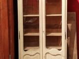 une armoire blanche avec une porte vitrée, près d'un mur rouge