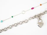 deux chaînes en argent ornées de pierres de différentes couleurs, posées sur un fond blanc