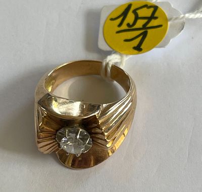 une bague en or sertie d'un diamant, posée sur une table blanche