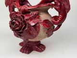 a red vase with a dragon on it on a white surface