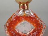 une bouteille en verre orange avec un bouchon doré, posée sur une table