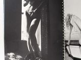 black and white photograph of a naked woman sitting on a bed