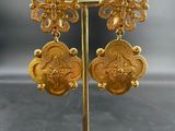 a pair of gold earrings on a stand