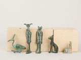 three bronze figurines of animals and a bird on a wooden block