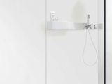 a glass shower with a black floor and a white wall