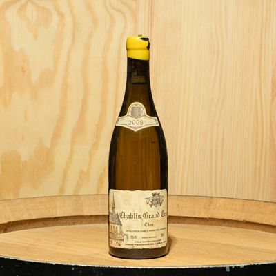 a bottle of wine sitting on top of a wooden barrel