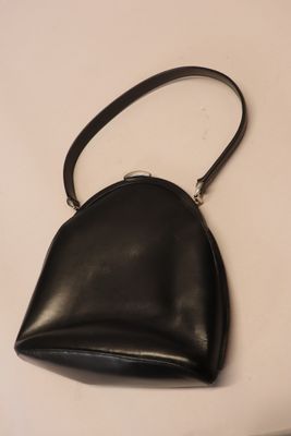 black leather purse on a white surface with a black strap