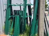 un tas de poteaux de clôture verts à côté d'un bâtiment