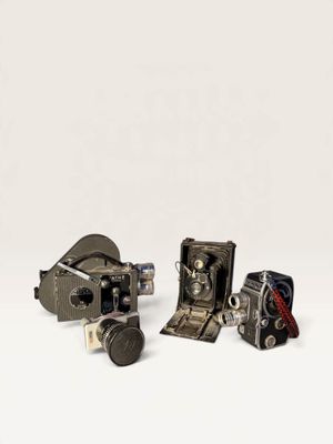 three old cameras sitting on top of a white surface