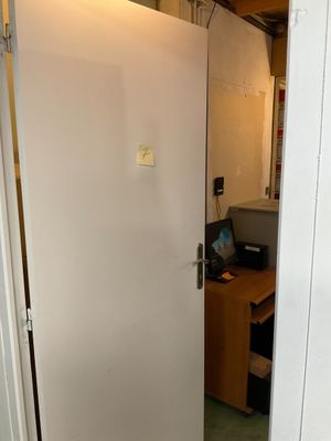 une porte blanche dans une pièce où se trouve un ordinateur posé sur un bureau