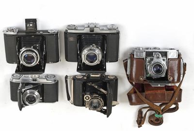several old cameras are lined up in a row on a white surface