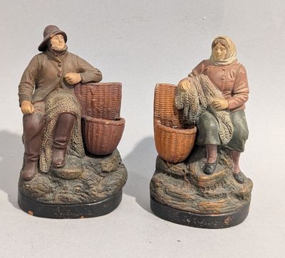 two figurines of a man and a woman sitting on a rock