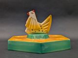 a yellow and green chicken figurine on top of a green base