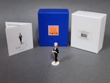une petite figurine représentant un homme en smoking, à côté d'une boîte bleue