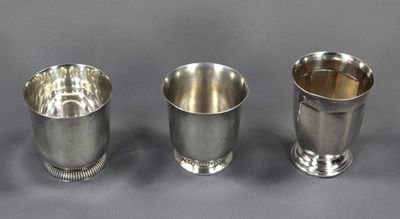 trois tasses en argent posées l'une à côté de l'autre sur une table