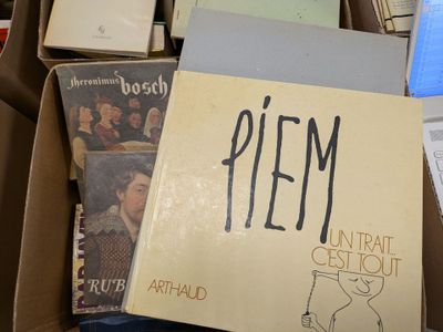 a pile of books in a cardboard box with a sign on it