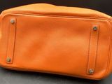 an orange leather purse sitting on top of a table