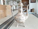une théière en argent posée sur une table dans un salon