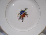 a white plate with a gold rim with a crest on it