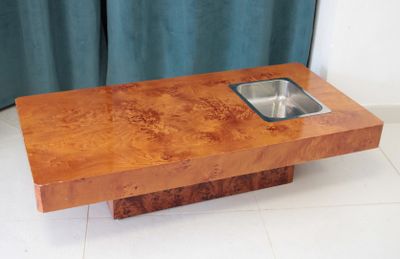une table en bois sur laquelle se trouve un évier, devant un rideau