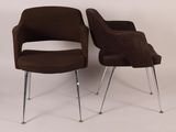 pair of brown chairs with chrome legs against a white wall