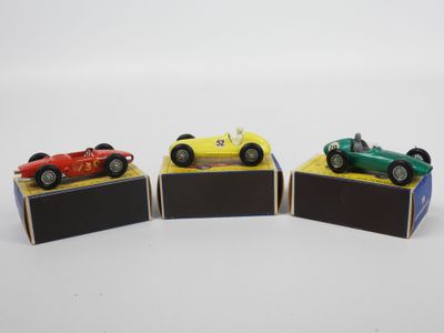 trois petites voitures sont exposées sur une surface blanche