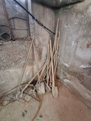 un tas de balais et de pelles dans un coin de la pièce