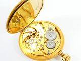 a gold pocket watch that is open on a white surface