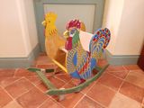 un cheval à bascule orné d'un coq, dans une pièce