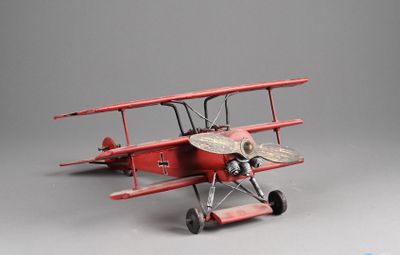 un petit avion rouge posé sur une surface grise