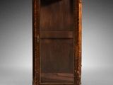 une vieille armoire en bois avec une porte vitrée, posée sur un pied