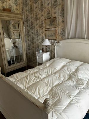 un lit blanc avec une couette blanche et un miroir dans un coin