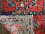 an image of a red rug with a blue border on a wooden floor