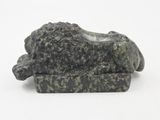 statue of a lion resting on a rock on a white surface