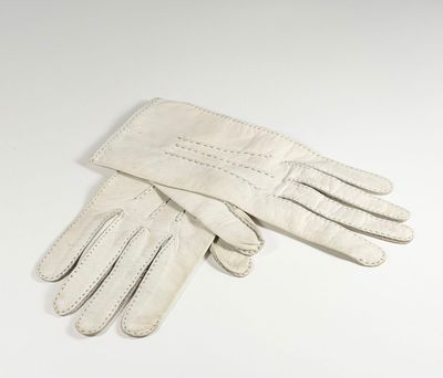 une paire de gants en cuir blanc posée sur une surface blanche
