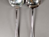 pair of silver spoons on a gray surface with a reflection of a person in the mirror
