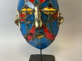 un gros plan d'un masque bleu et rouge posé sur un support métallique