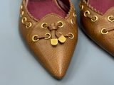 a pair of brown shoes with gold decorations on them