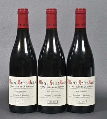 three bottles of red wine are lined up on a gray surface