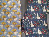 two neck ties with animals and flowers on them on a table