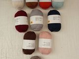 many balls of yarn sitting on a towel on the floor
