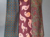 three ties with different designs on them on a gray surface