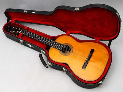 une guitare dans un étui, posée sur une surface blanche