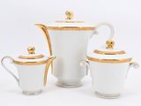 three pieces of white and gold tea set on a white surface