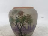 a vase with a painting on it sitting on a table