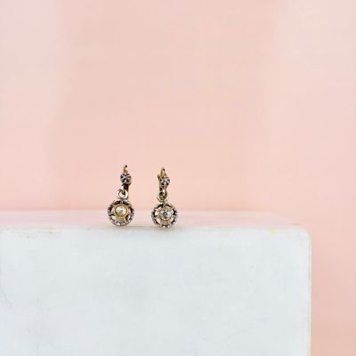 une paire de boucles d'oreilles posée sur un bloc blanc