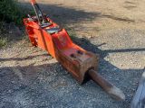 a log spliter sitting on the ground next to a wooden fence