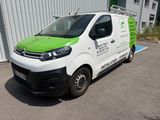 une camionnette blanche aux finitions vertes garée devant un immeuble