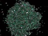 some green crystals are scattered on a black surface